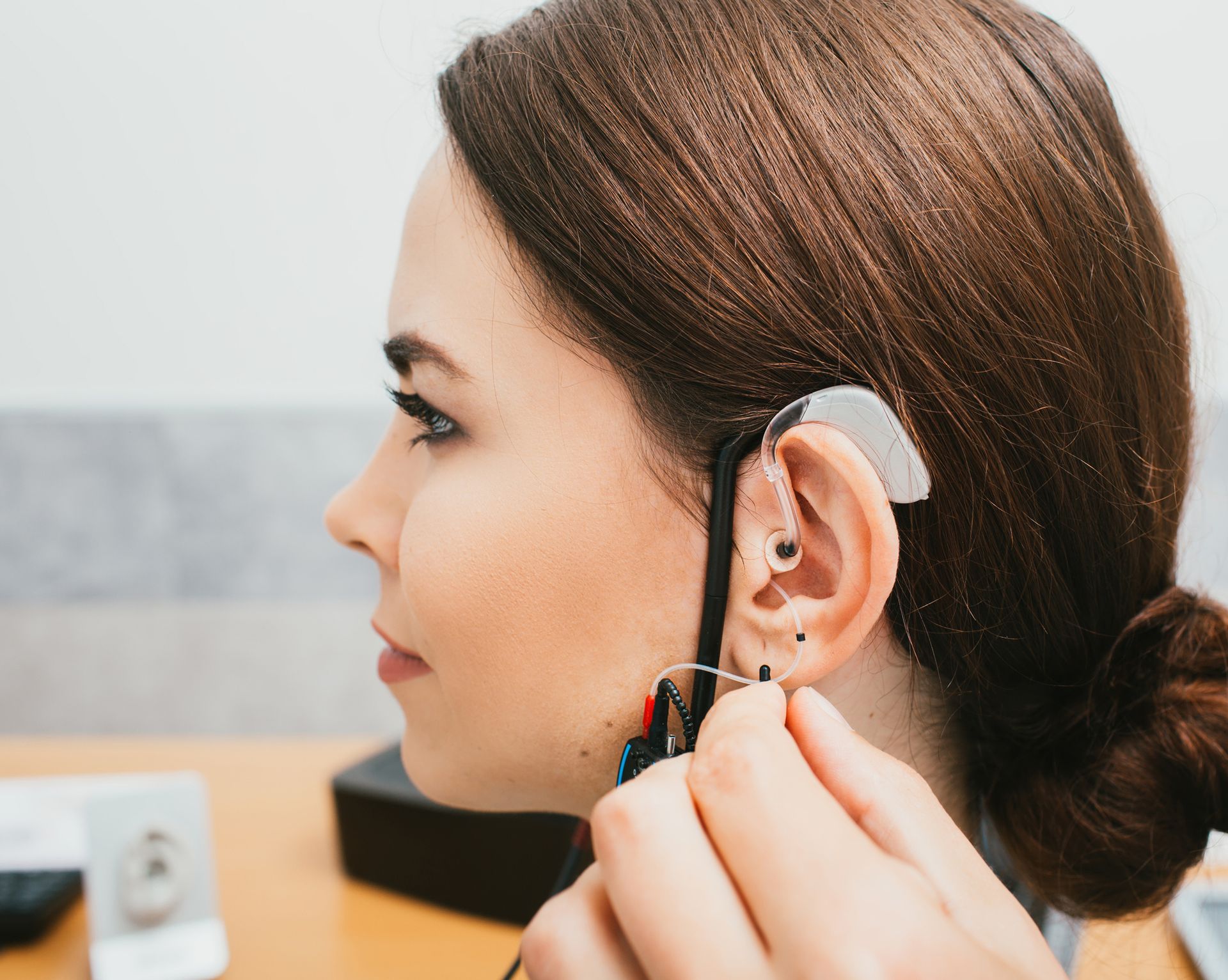 A person is being fitted with a hearing aid behind the ear.