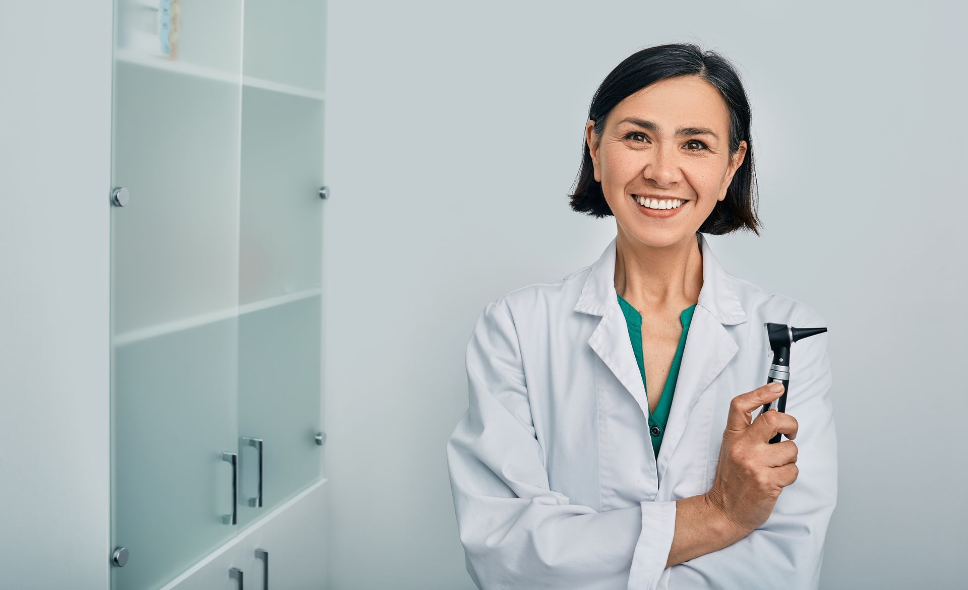 A woman audiologist with an otoscope standing in an audiology clinic A woman audiologist with an otoscope standing in an audiology clinic