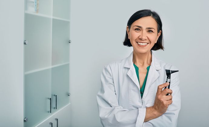 A woman audiologist with an otoscope standing in an audiology clinic