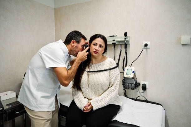 View of an audiologist revising the ear of a female patient.