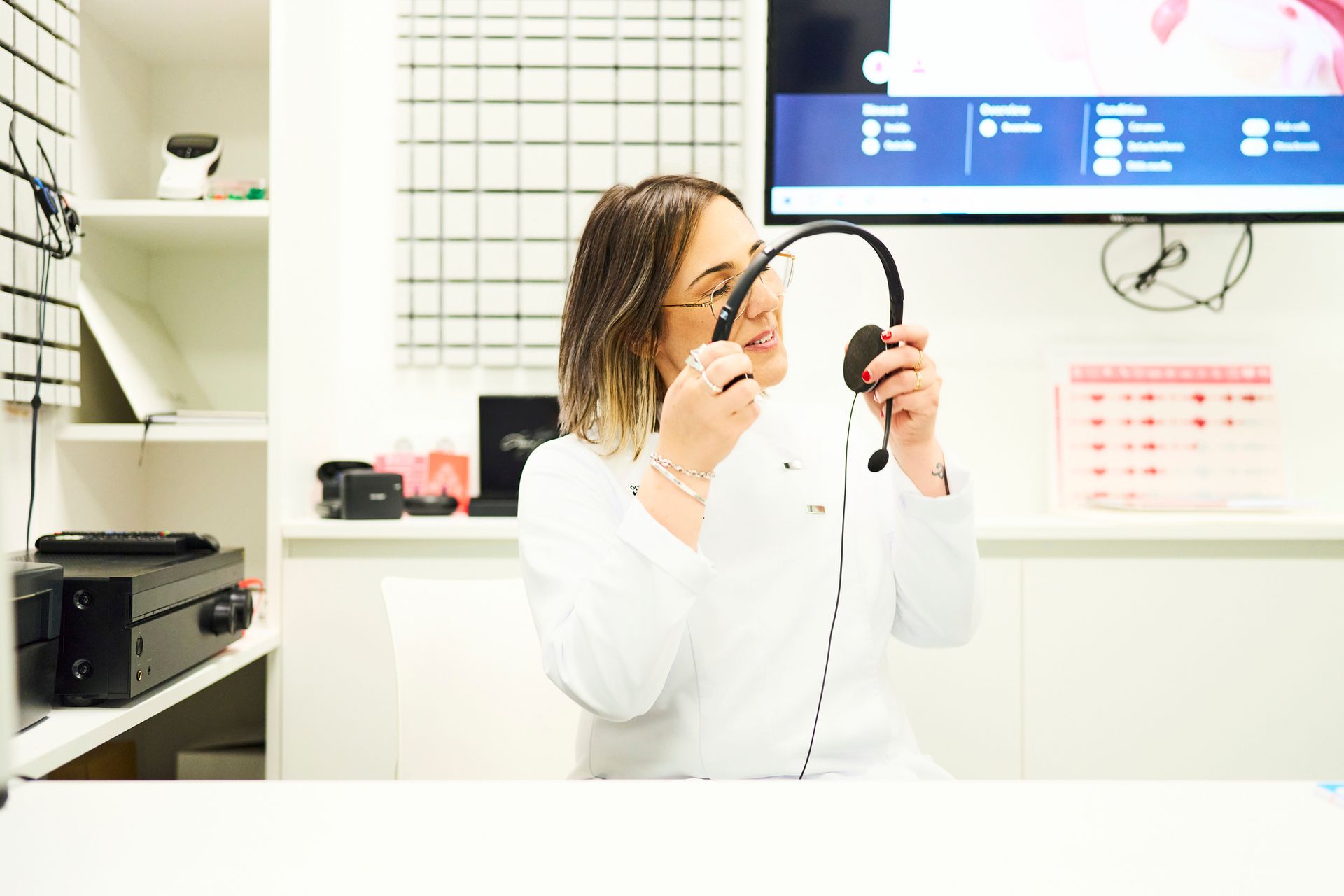 An audiologist is preparing a headset for a hearing test. An audiologist is preparing a headset for a hearing test.