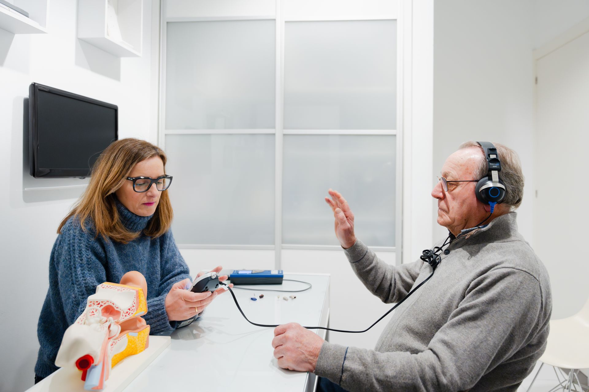 An ear doctor checking hearing loss on an elderly patient in a clinic.