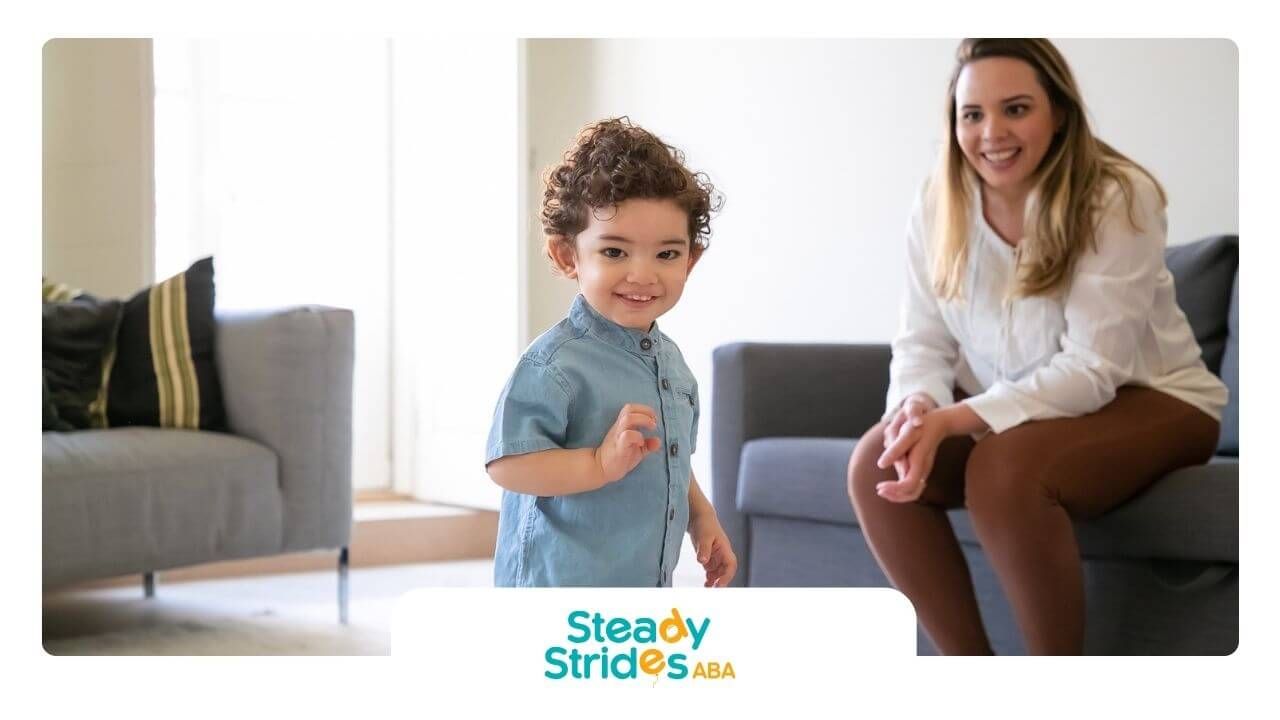 An ABA therapist is sitting on a couch next to a young boy in ABA therapy.