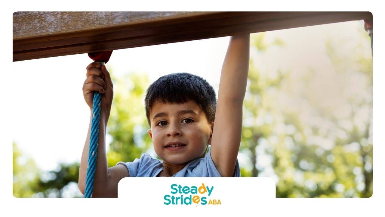 Boy with autism holding blue rope outdoors, smiling.
