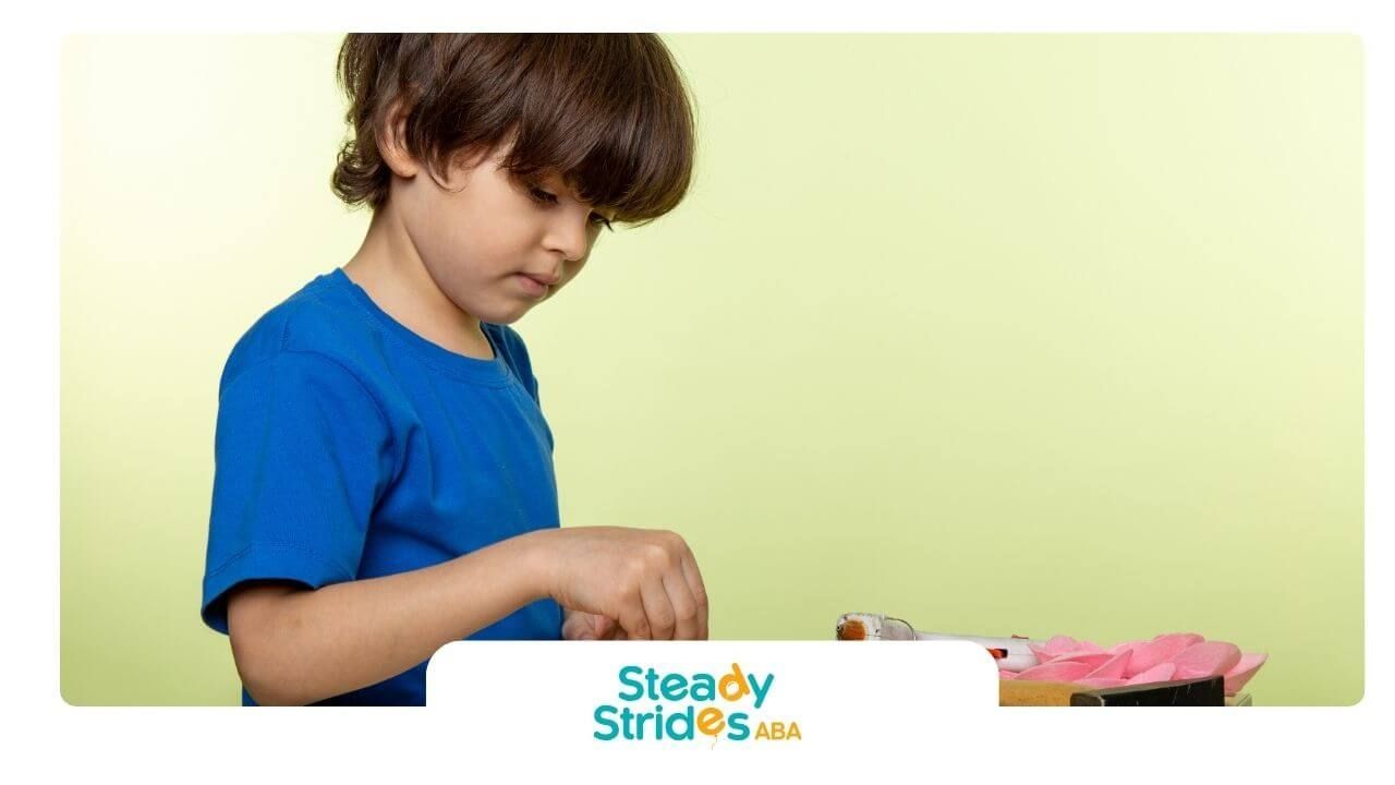 Autistic boy concentrating while using simple tools & assembling a small wooden project at a table.