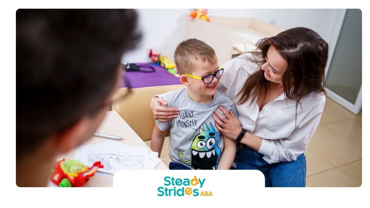 Smiling therapist interacting with am autistic boy wearing glasses during a positive ABA session