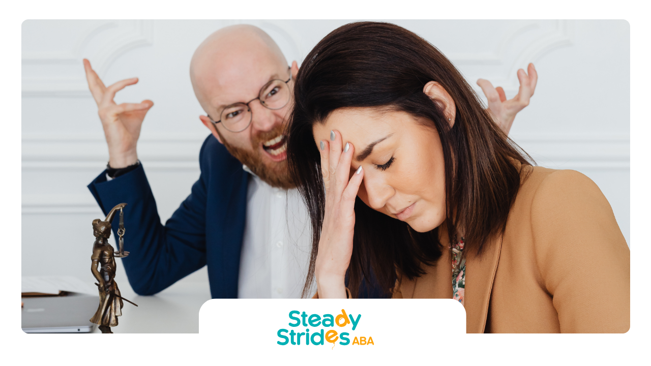 Man yells behind woman with hand on forehead; both in office, stressed.