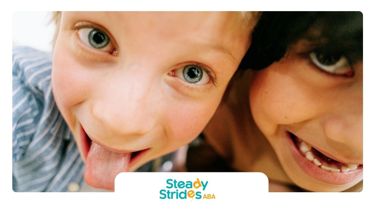 Close-up of two autistic kids smiling and making faces during an ABA therapy session in Texas.