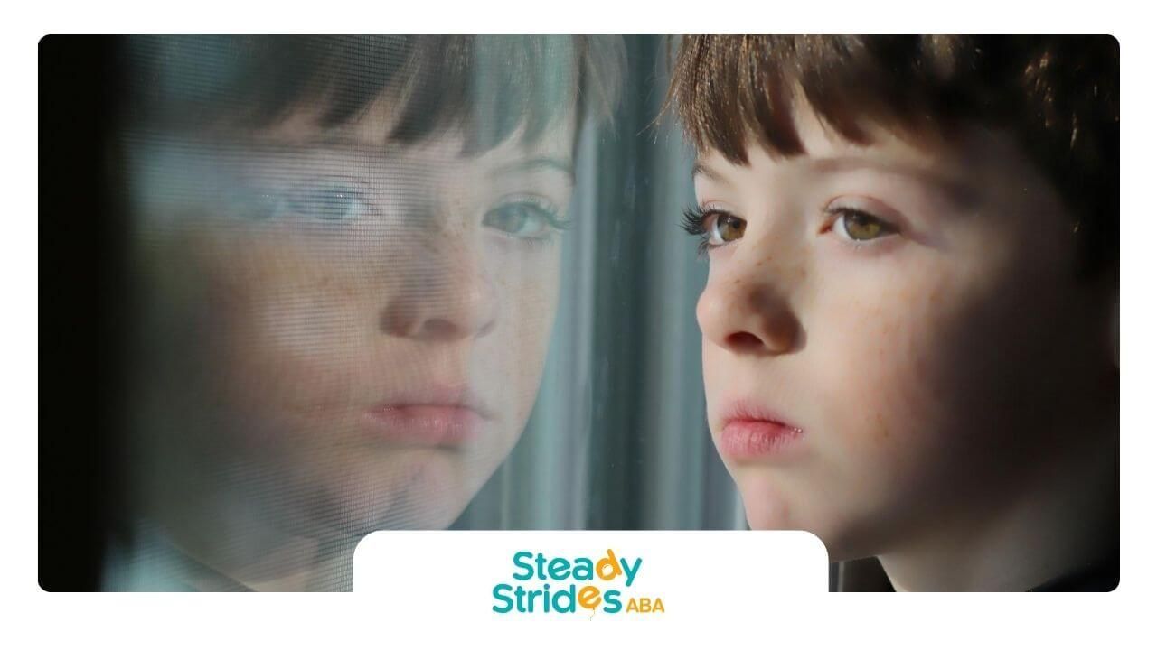 Young boy with autism staring out the window with reflection on glass.