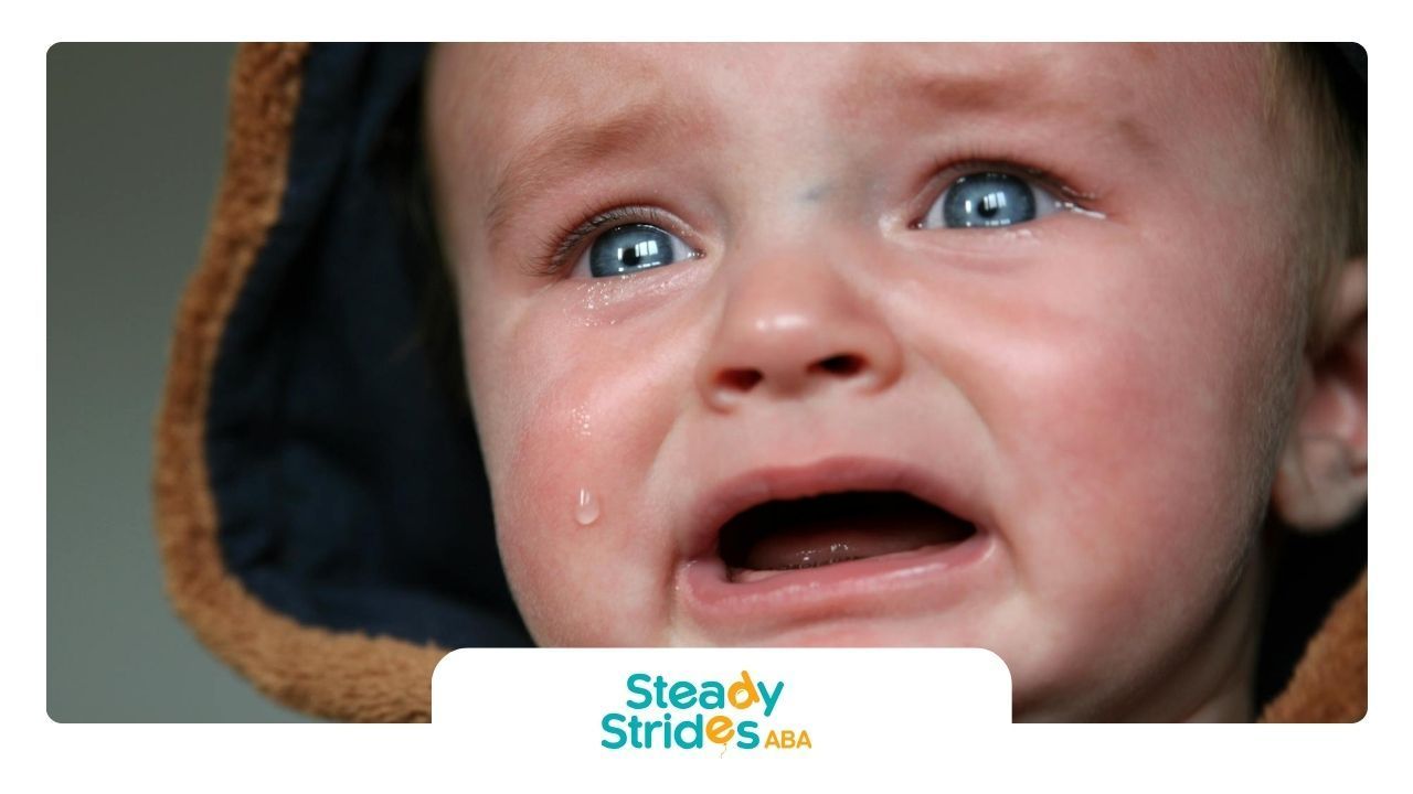 A baby with autism crying with tears streaming down their cheeks, wearing a hooded outfit in Texas.