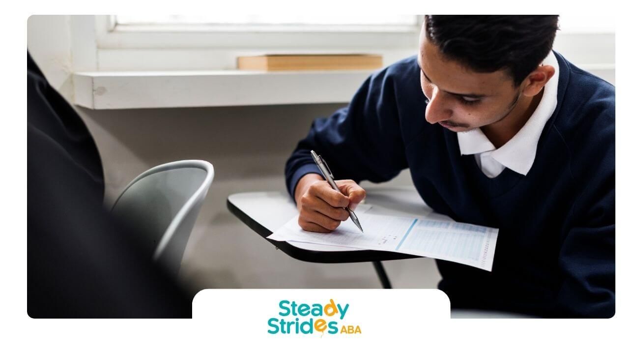 ABA Student concentrating while completing written exam on paper in classroom testing environment.