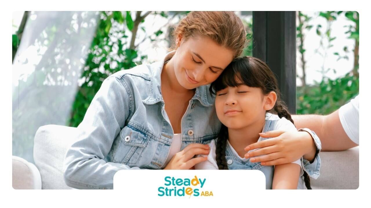 A BCBA and a little girl are sitting next to each other on a couch in ABA therapy.