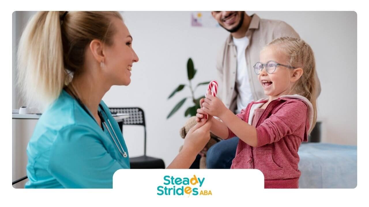 A nurse is talking to a little girl while a father and BCBA look on.