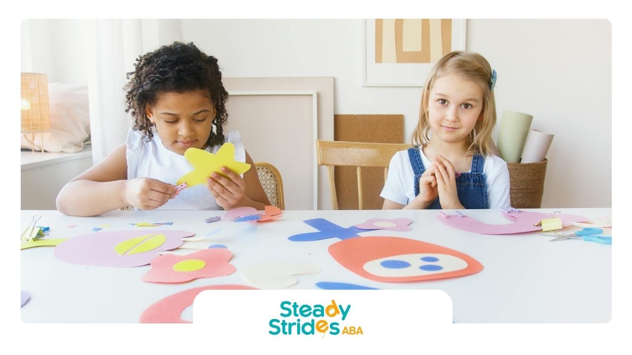 Two young autistic girls are making crafts at a table during center-based ABA therapy in Texas.