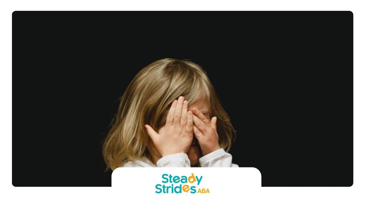 A little girl is covering her eyes with her hands.