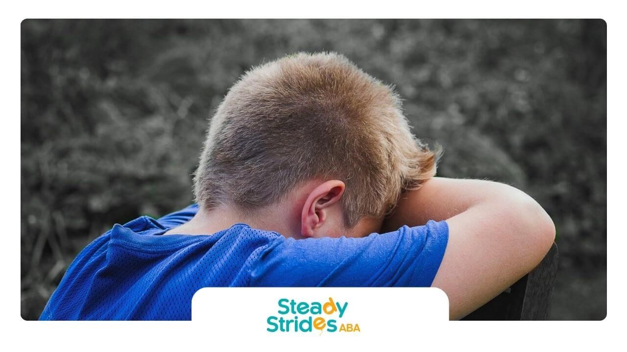 Autistic boy with his head resting on his arms, showing signs of sadness or after therapy.