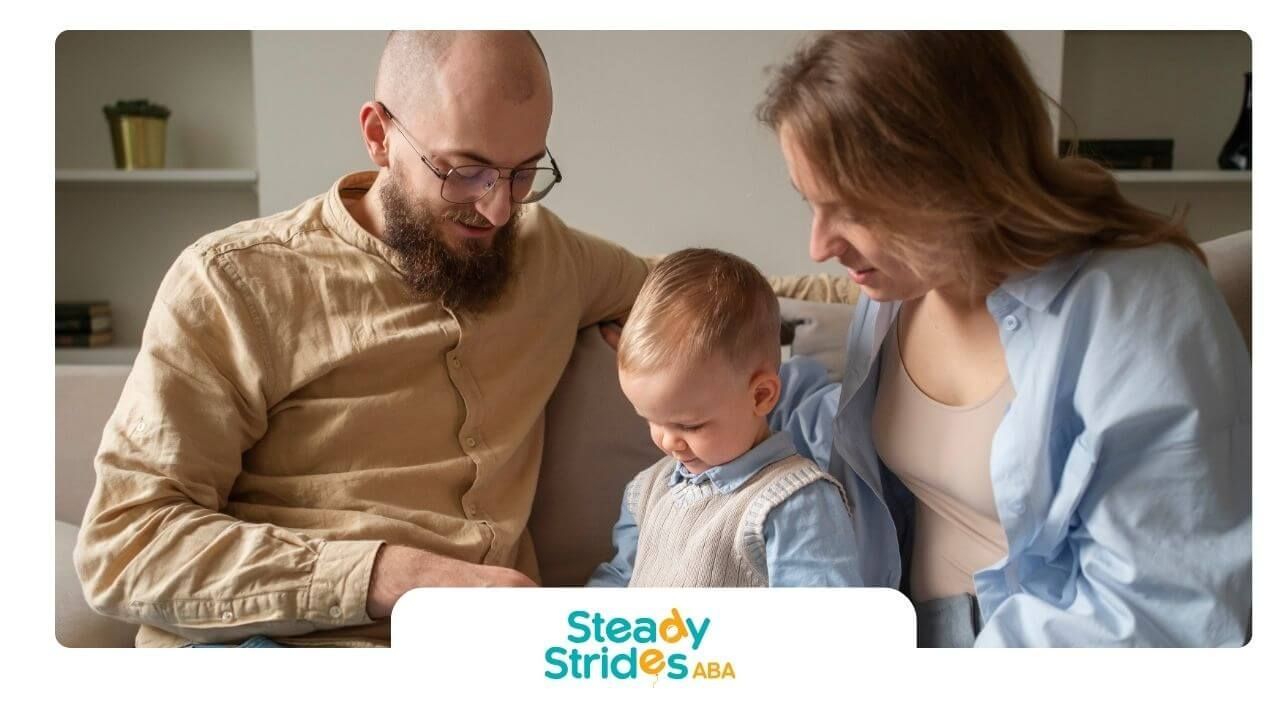 Therapists sitting with autistic toddler on a couch helping him play with a colorful toy puzzle.