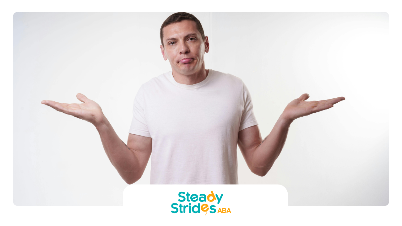 Man with outstretched arms, tongue out, wearing a white t-shirt, white background.