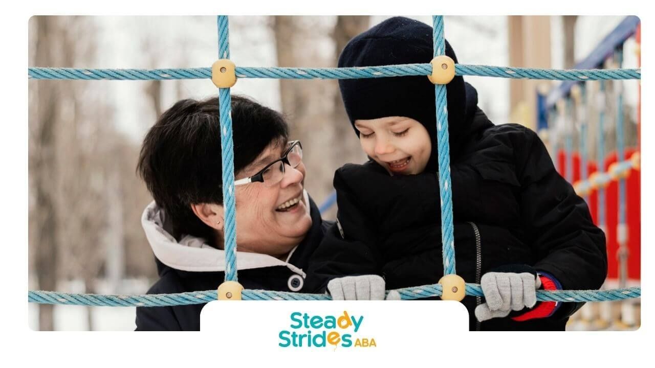 Therapist helps autistic boy climb rope playground during joyful winter playtime in Texas.