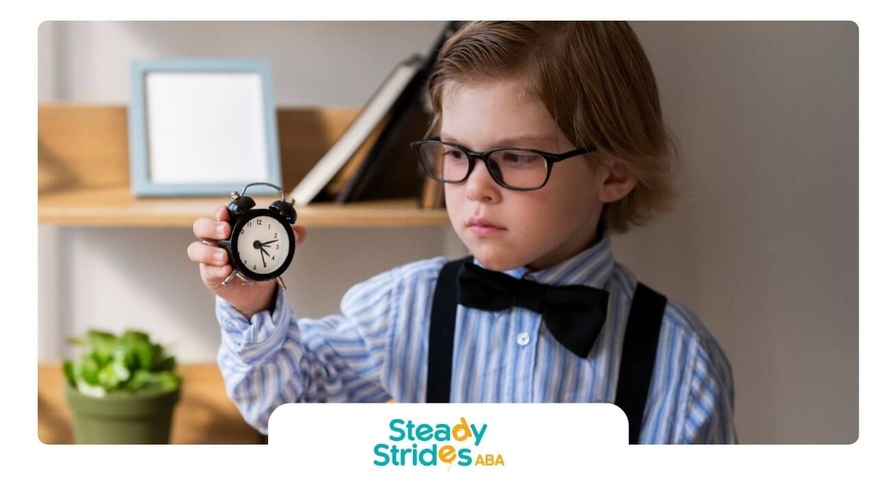 Autistic boy wearing glasses holding small alarm clock, symbolizing time management and routines.