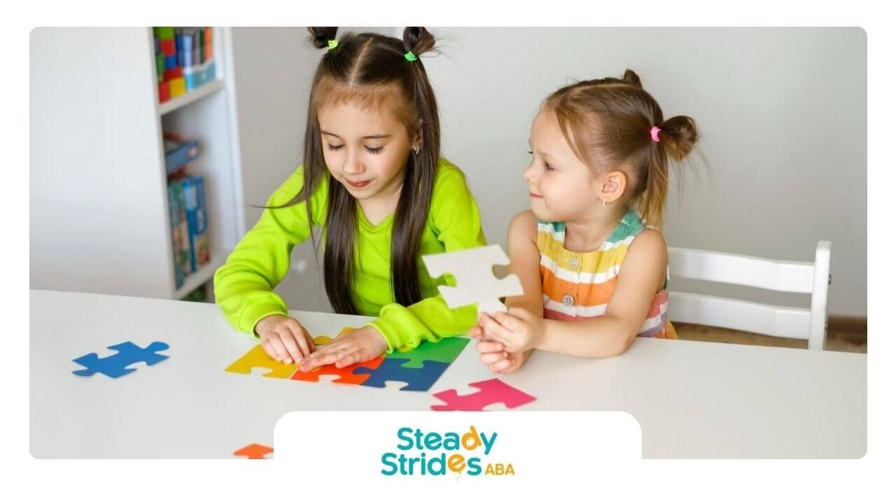 Two young girls with autism working on colorful jigsaw puzzle pieces at a table.