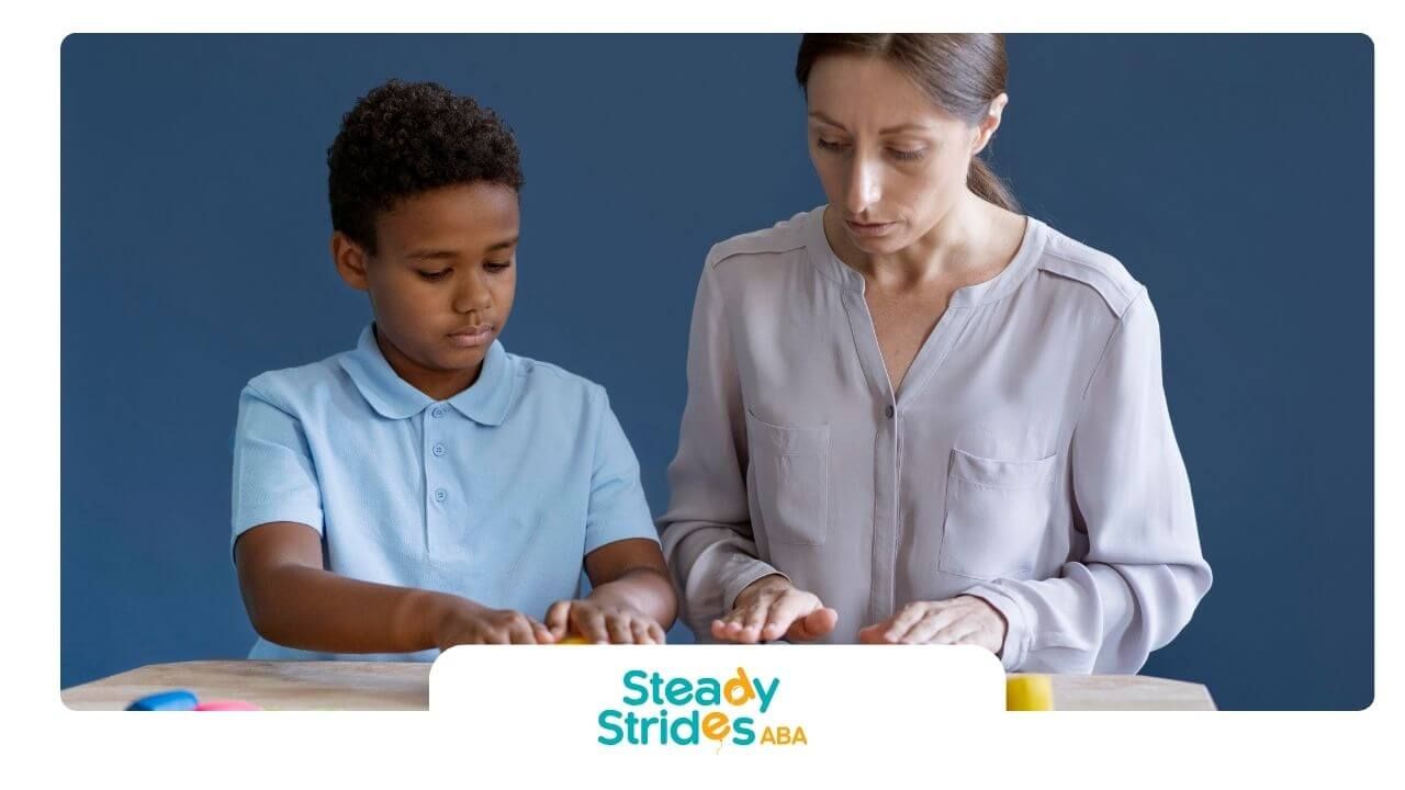 The therapist guides the child using playdough to build fine motor and sensory skills during therapy
