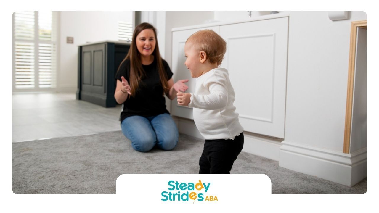 An ABA therapist is sitting next to a baby in a living room.