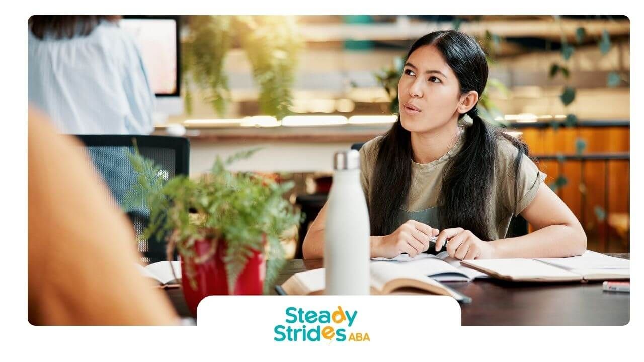 Focused ABA student studying with open books and notebook at desk in modern learning space.