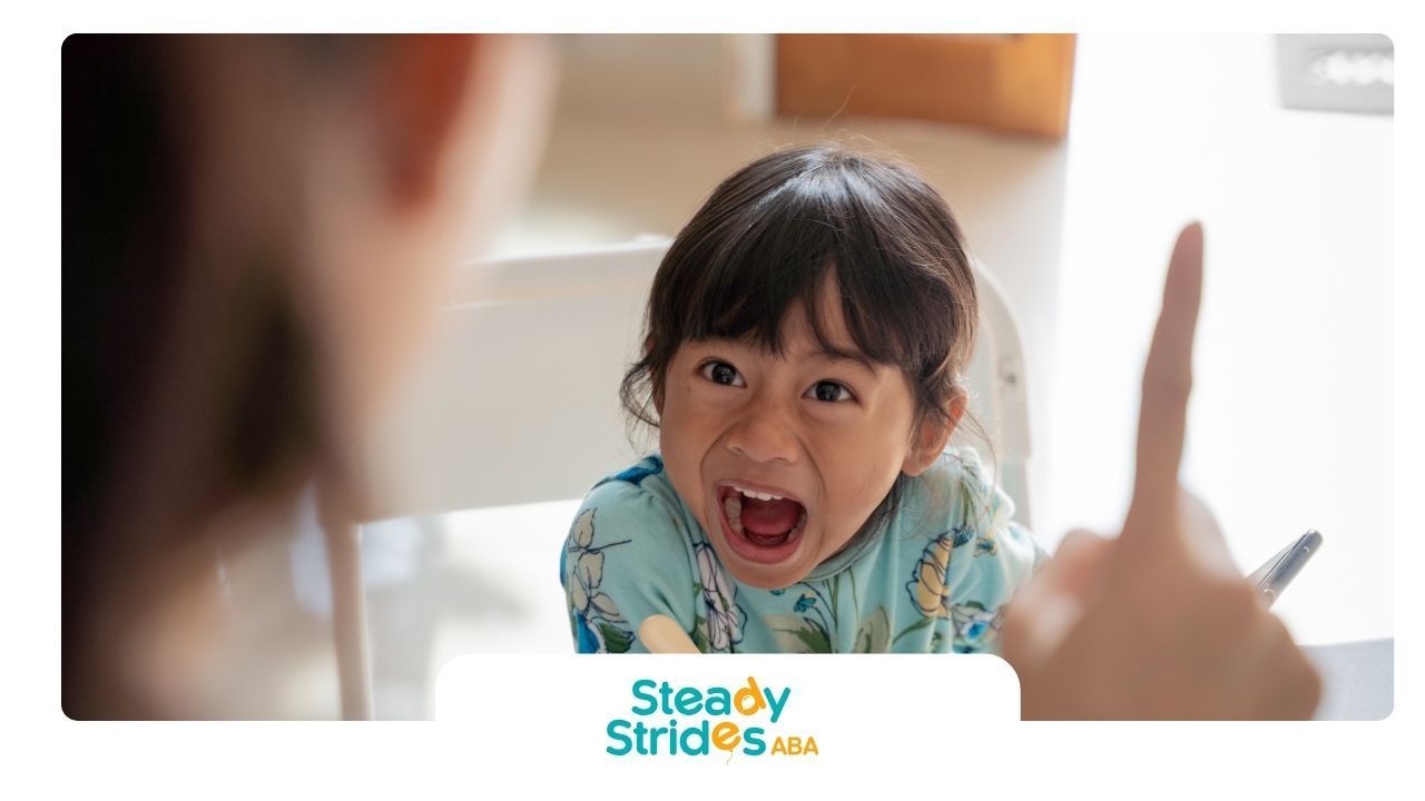 Child with mouth open, yelling, facing a person pointing a finger.