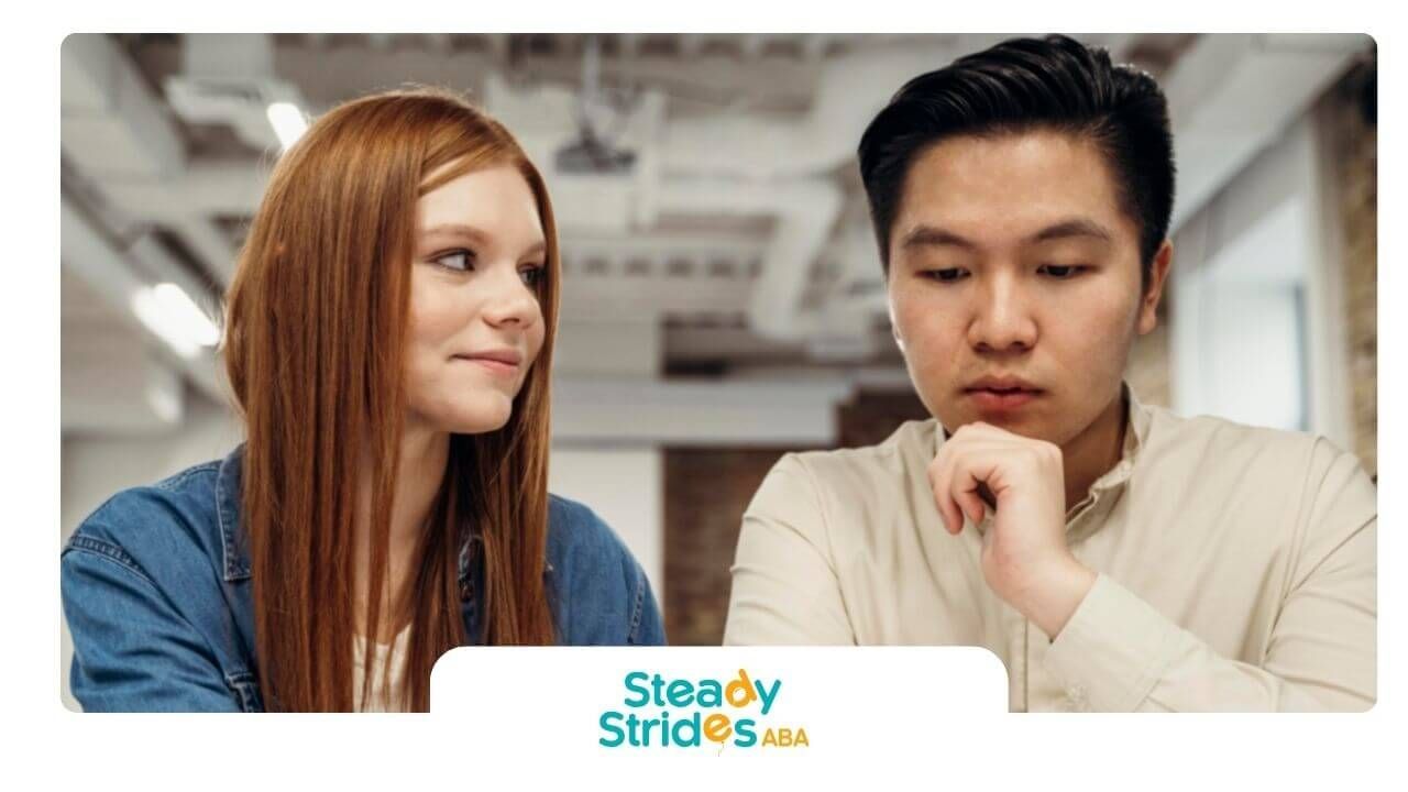 ABA students collaborating over notes at a desk, discussing ideas and reviewing materials together.