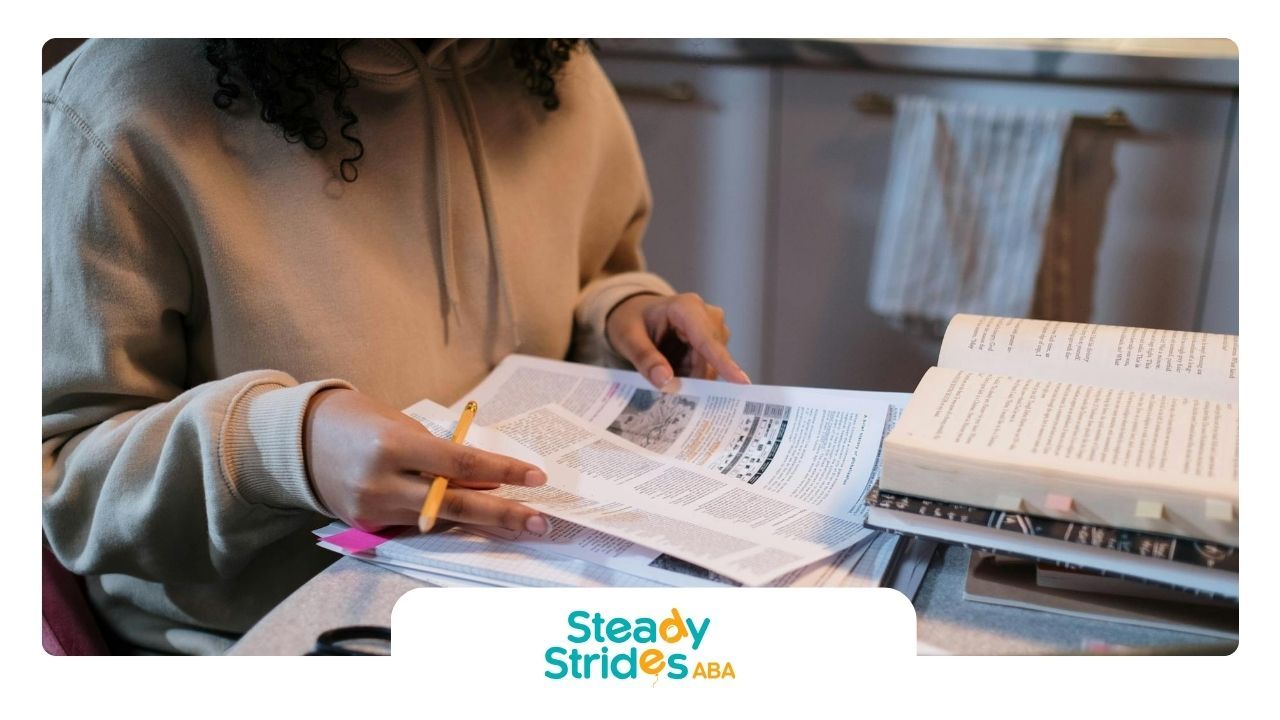 An aspiring RBT in a hoodie studying with books, notes, and a pen at a cluttered table in Texas.