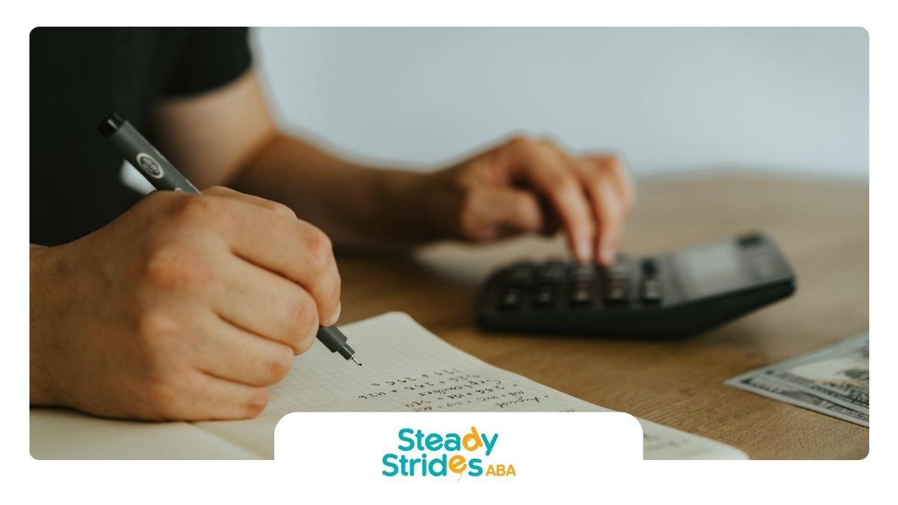 Parent of an autistic child writing in notebook while calculating ABA therapy cost on a desk in TX.