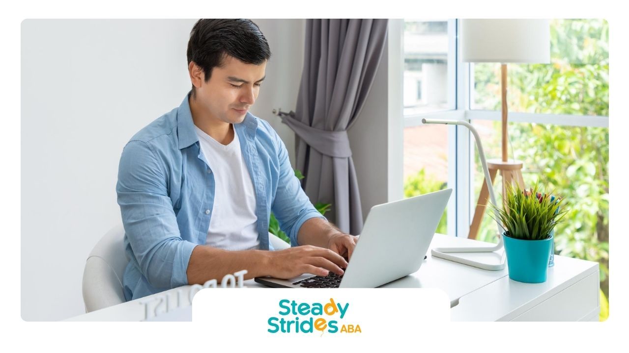 An RBT is sitting at a desk using a laptop computer to renew his RBT certification.