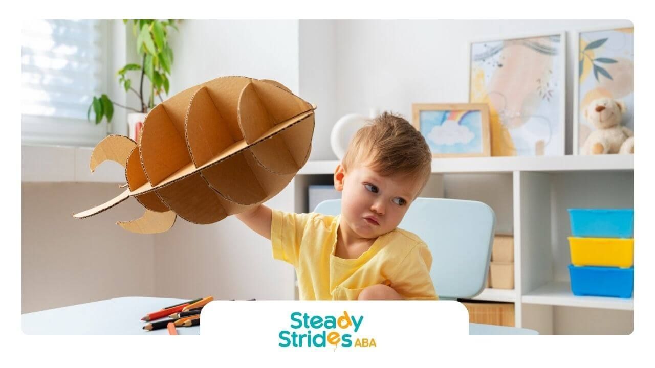 A young boy with autism is holding a cardboard leaf in his hand.