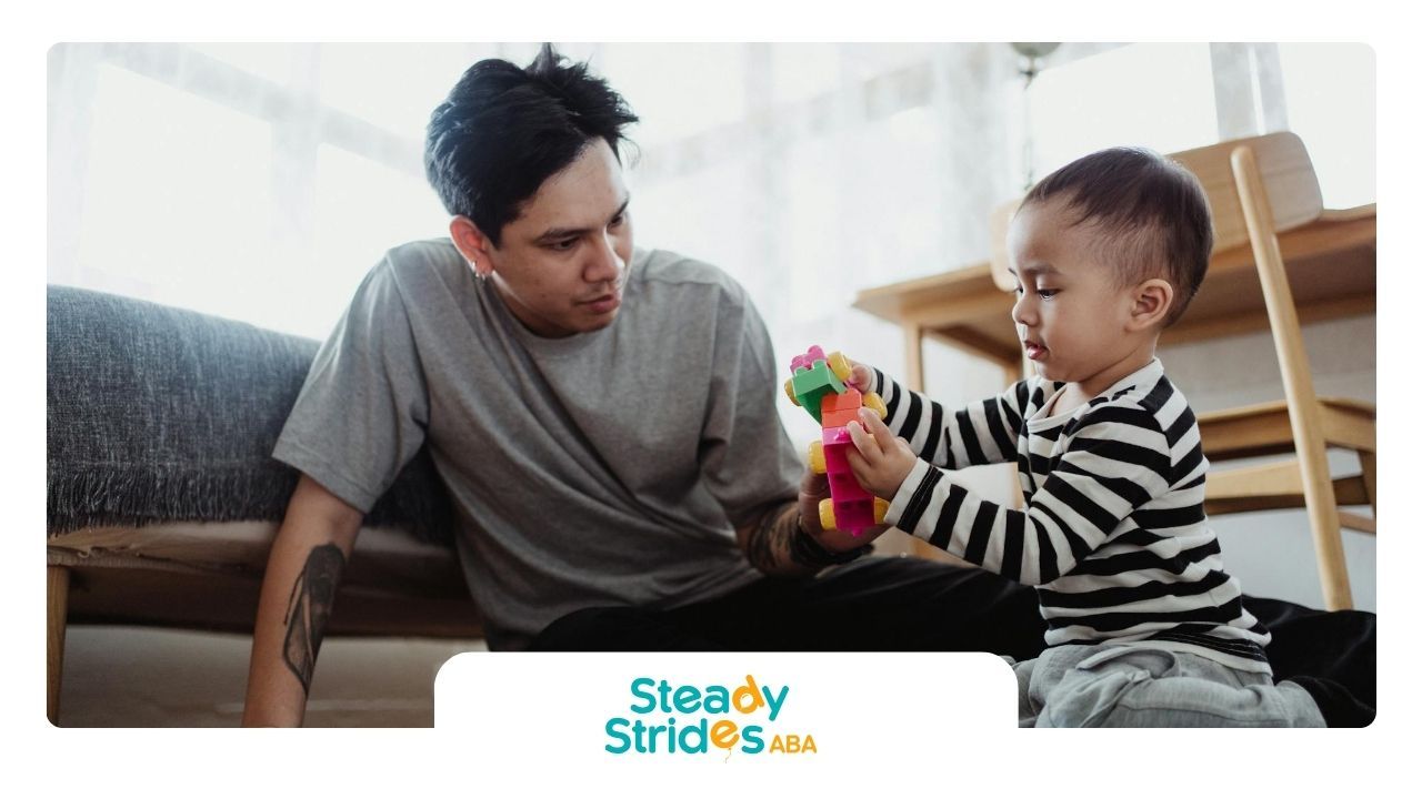 ABA therapist and autistic child building with colorful toy blocks during in-home ABA therapy in TX.