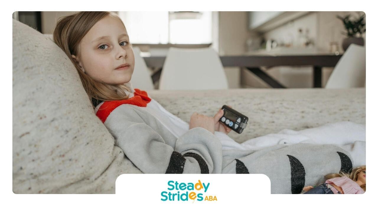 The autistic child laying on the couch, looking slightly disengaged with a doll beside them.