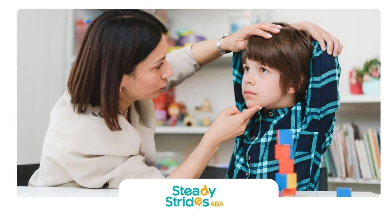 Specialist gently supports an autistic boy’s chin while assessing communication or articulation