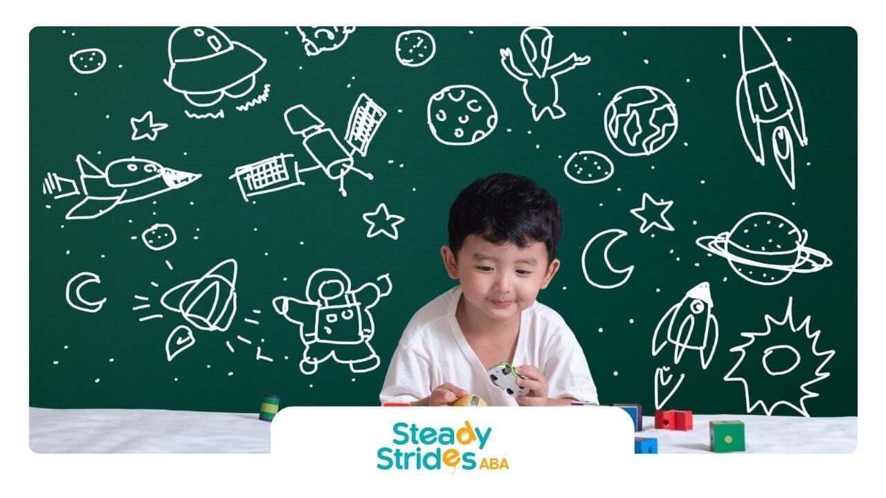 Boy with autism playing with colorful blocks in front of a chalkboard with space drawings.