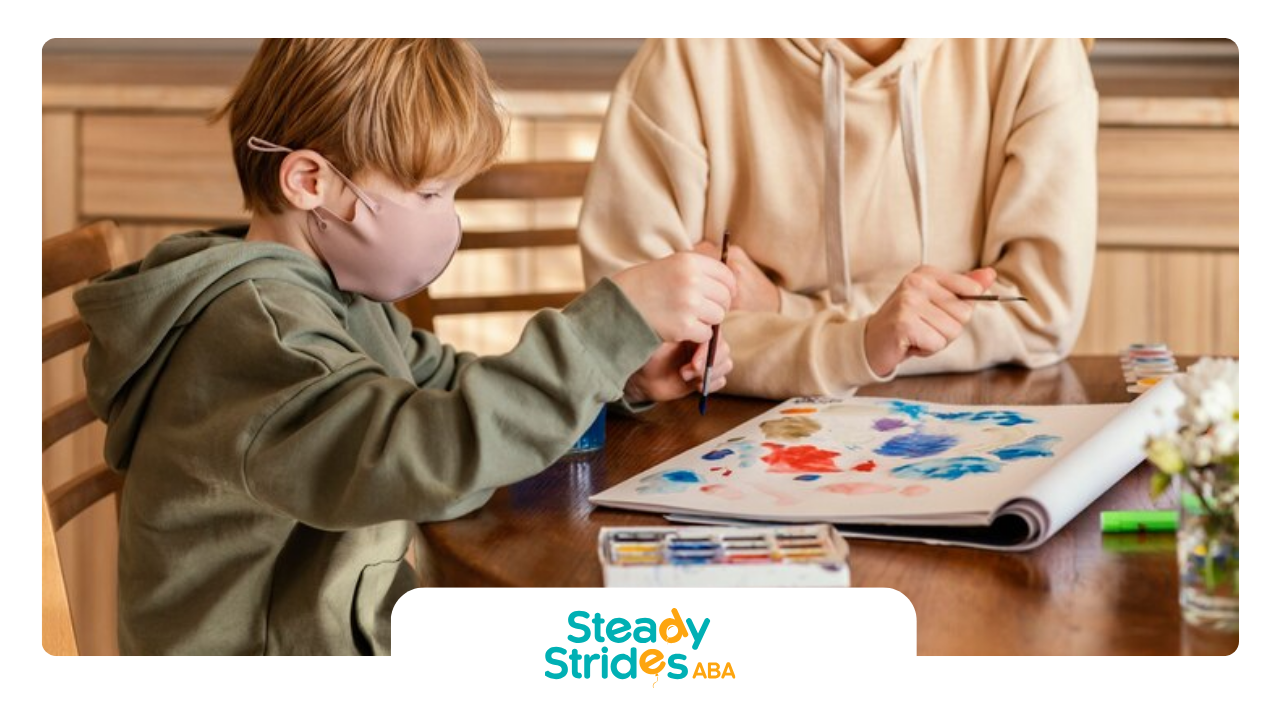 A boy wearing a mask is sitting at a table with an RBT during ABA therapy.