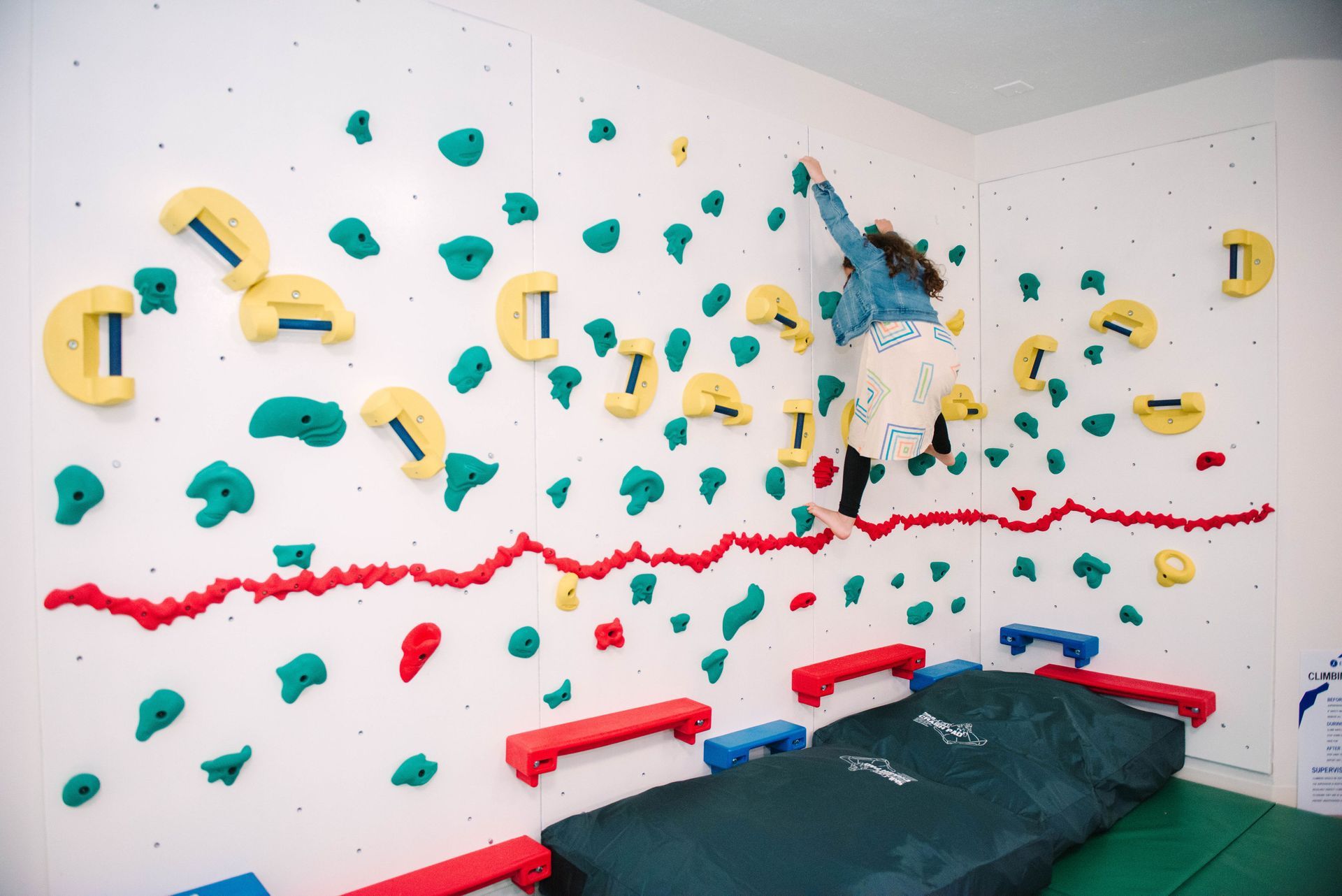 A person is climbing a climbing wall in a room.