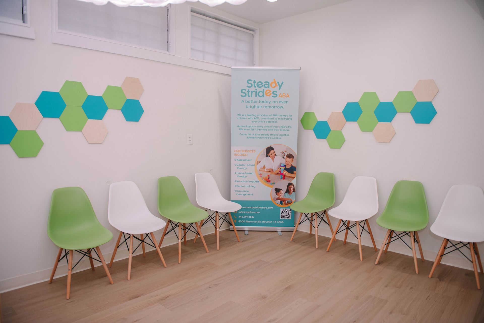 A waiting room with green and white chairs and a sign on the wall.