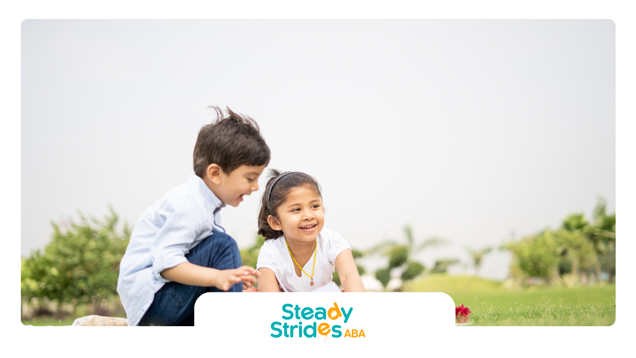A boy and a girl are sitting on a rock in a park.