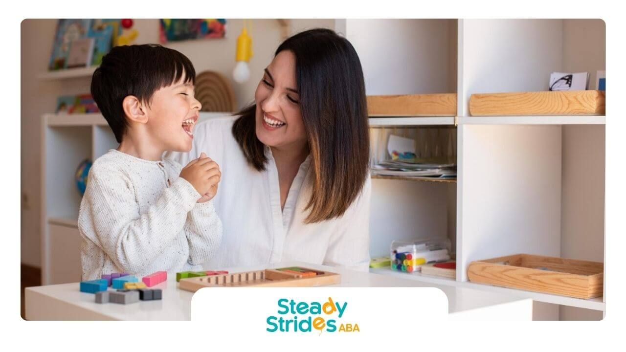 A BCBA and an autistic child are sitting at a table playing with toys.