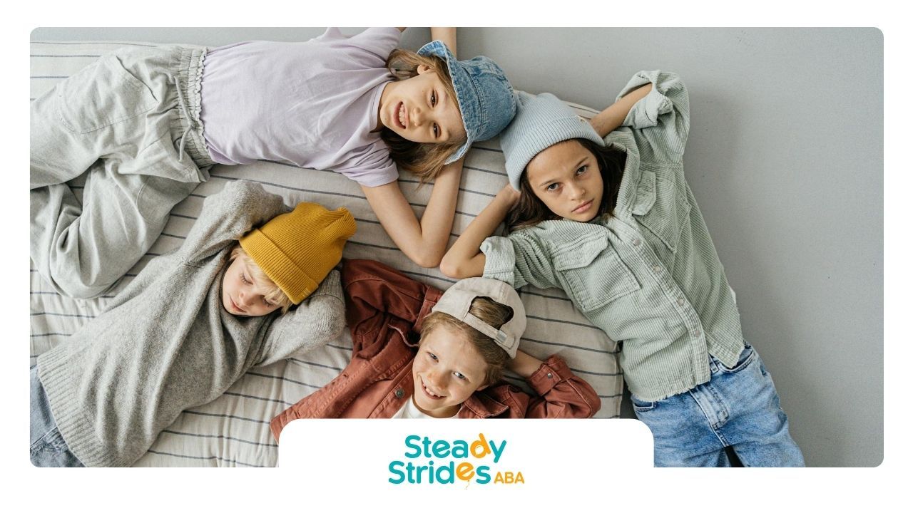 Four autistic children lying on a bed, dressed in casual outfits, looking happy together in Texas.