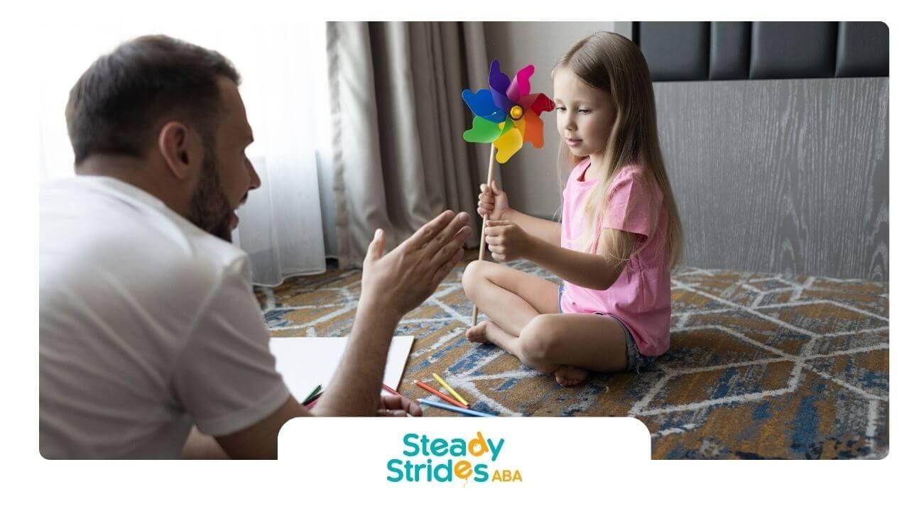 Therapist encouraging autistic girl holding a colorful pinwheel toy, supporting engagement & focus