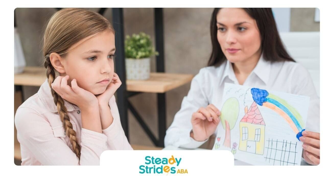 Autistic girl looking thoughtful as therapist discusses her colorful house drawing in therapy.