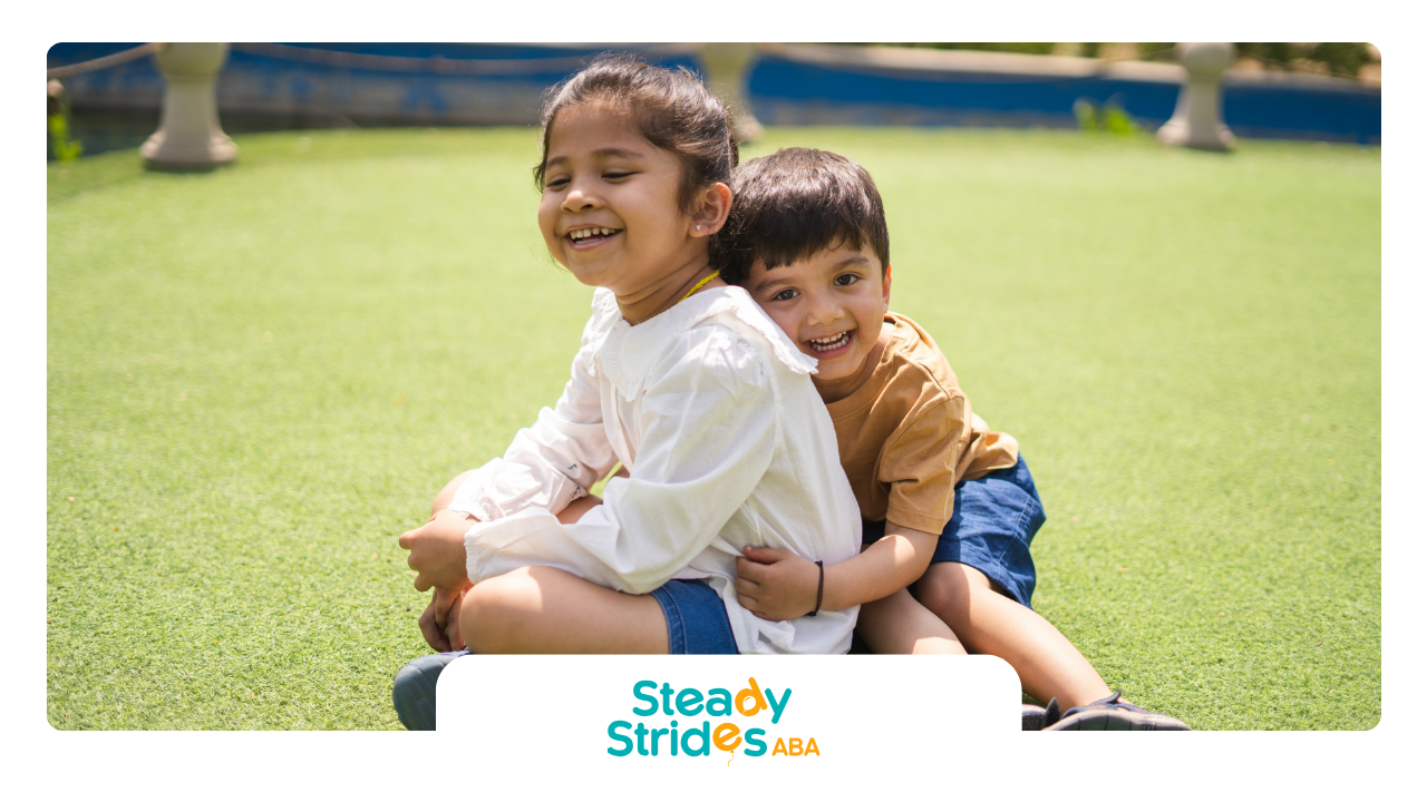 A boy and a girl are hugging each other on the grass.