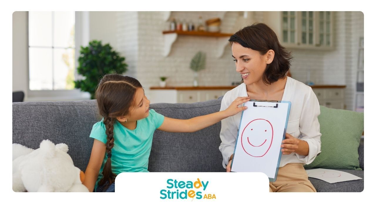 A woman is sitting on a couch holding a clipboard with a smiley face drawn on it.