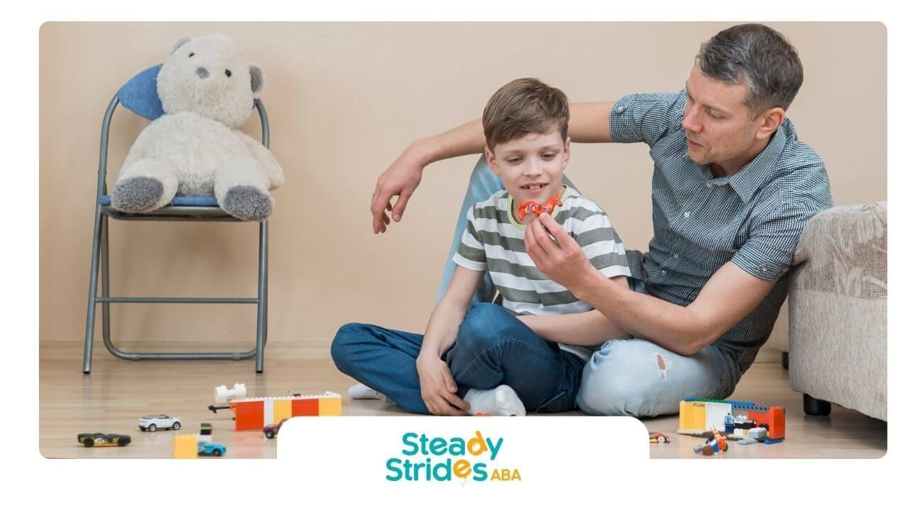 Therapist sitting on floor playing with autistic boy and toy cars in supportive home environment.