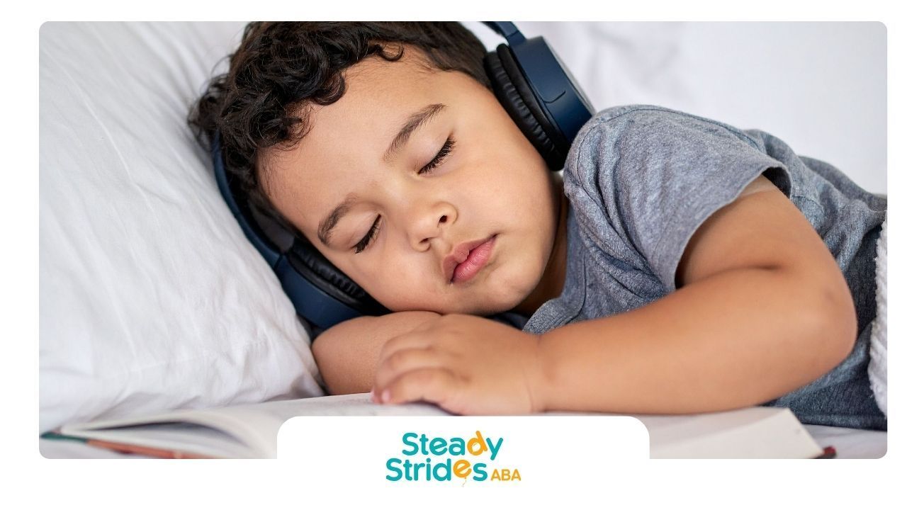 Boy asleep in bed wearing headphones, with a book open in front of him.